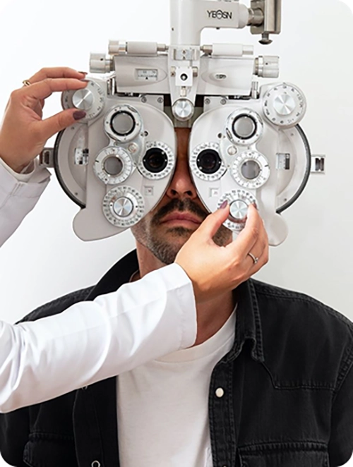 photo d'un homme qui est installé et qui se fait osclté avec un appareil par un opticien